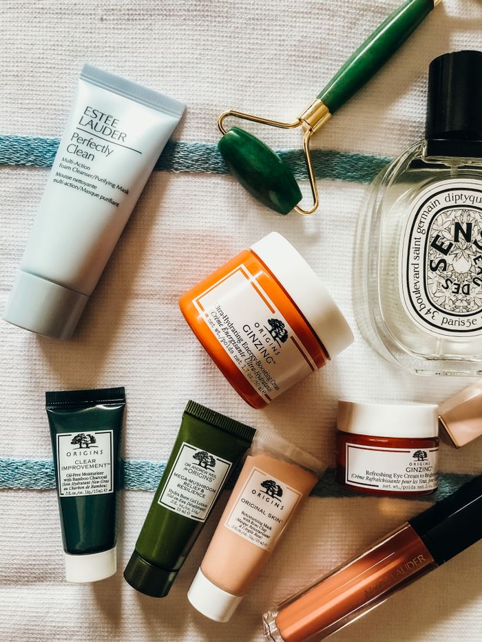 Top view of skincare products and jade roller on a textured surface, showcasing various brands.